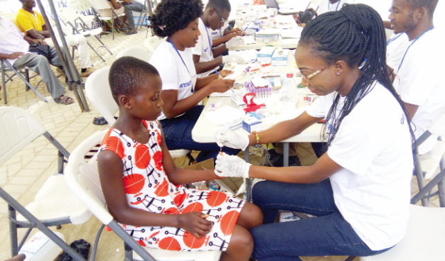 A health professional attending to a young girl while other health workers are engaged in documentation